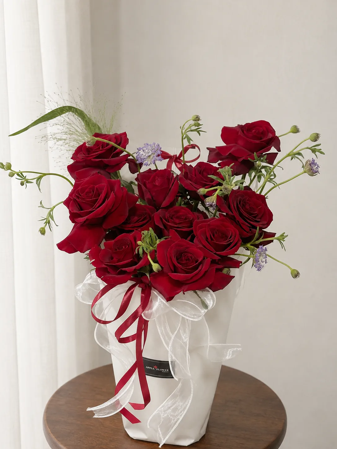 A hand-tied bouquet of red roses in white wrapping