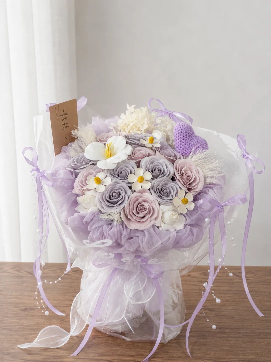 A soap flower bouquet in lilac and cream, finished with a crochet heart